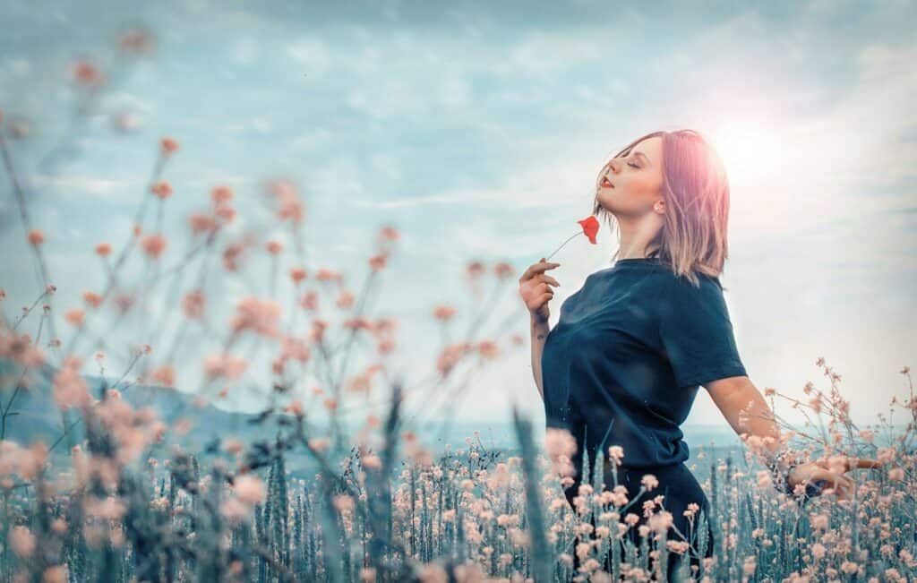 Happy woman holding red flower reflecting experience from a wellness strategy session