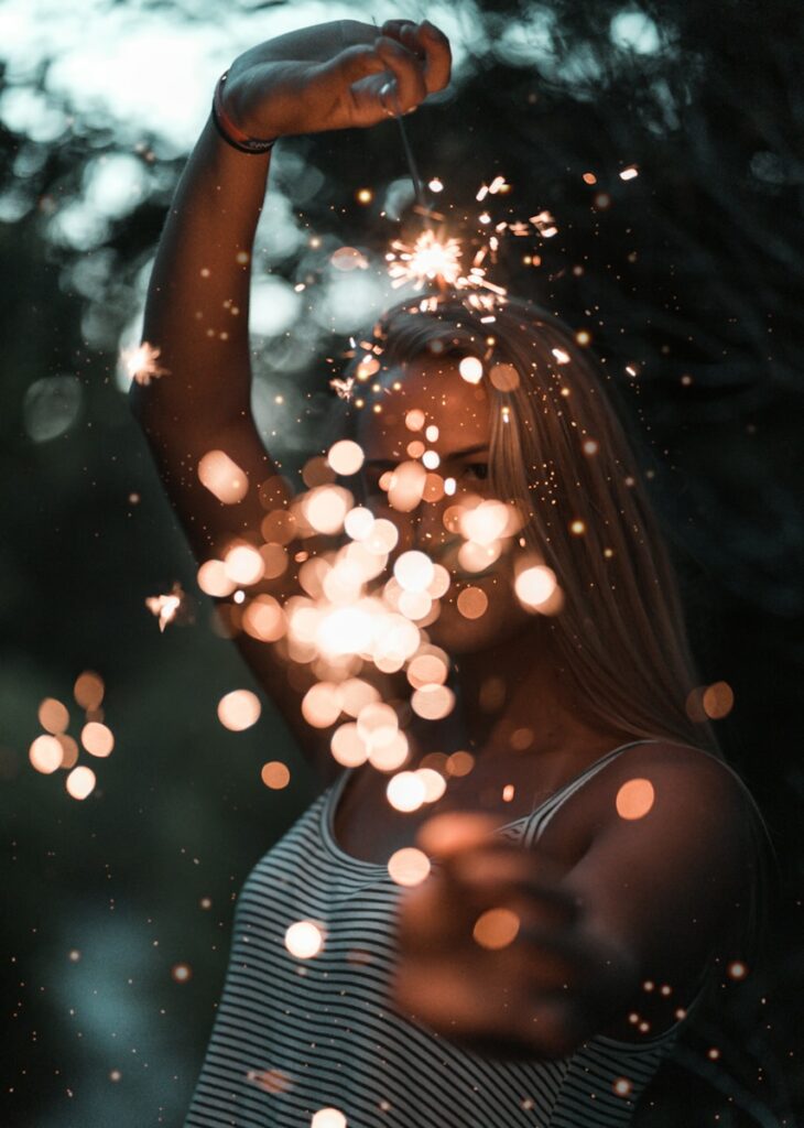 woman holding sparklers representing magic instead of the mundane