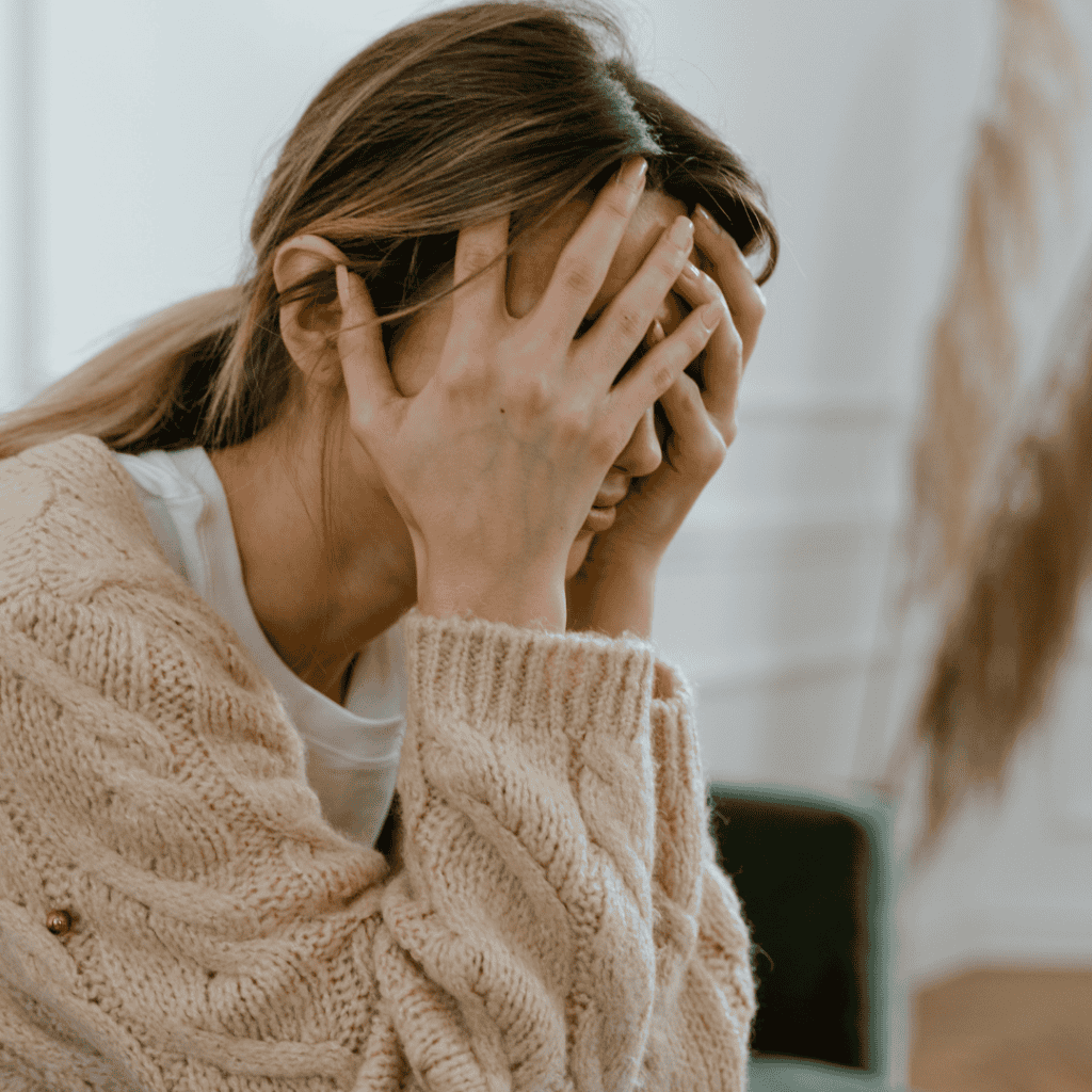 Woman looking frustrated wanting less stress as her face is in her hands